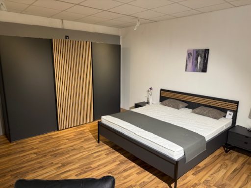 Schlafzimmer mit einem Doppelbett, Nachttischen und einem großen Schrank. Holzfußboden.